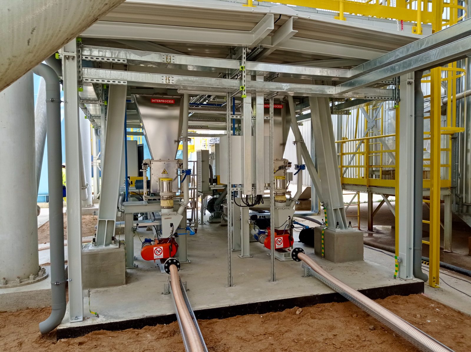 Dozowniki śrubowe loss-in-weight pod silosami w rafinerii — instalacja zewnętrzna z odbiorem materiału transportem pneumatycznym